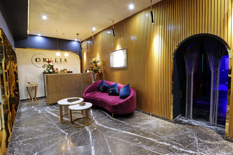 Accueil du spa Orélia à Marrakech, avec comptoir, canapé pourpre et mur doré