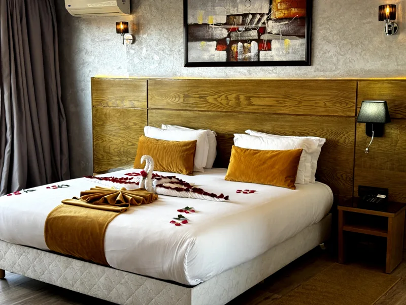 Lit double de la Chambre Deluxe de Stars Hotel & Spa Marrakech, avec coussins ocre et tête de lit en bois