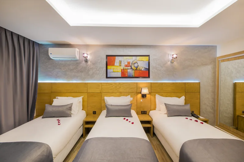 Les trois lits simples de la Chambre Triple, sous le tableau et l’éclairage du plafond