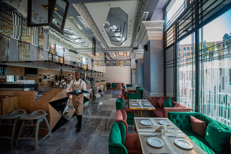 Membre de l’équipe de Pensée portant un plateau dans la salle du restaurant à Marrakech