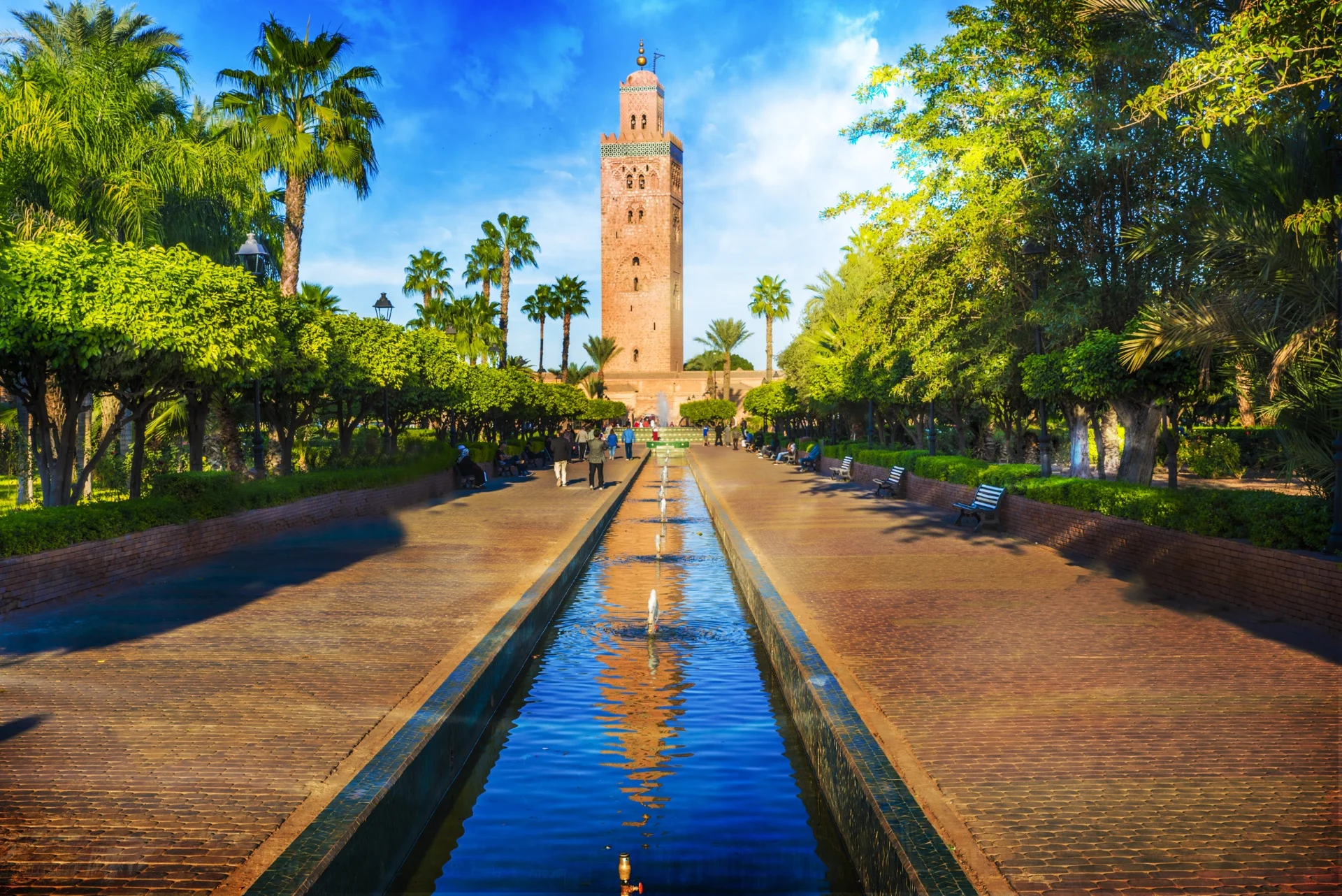 Minaret de la Koutoubia à Marrakech, vu depuis l’allée bordée de palmiers et son bassin central