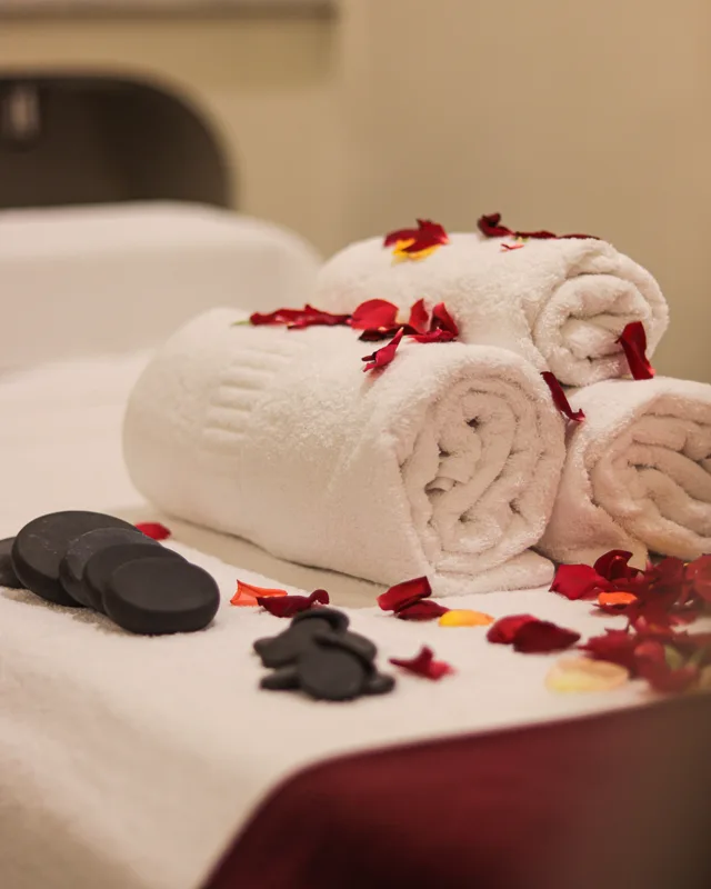 Rolled towels, massage stones and petals on a treatment table at Orélia spa in Marrakech